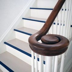 a wooden handrail on the bottom of a stair case with blue and white stripes