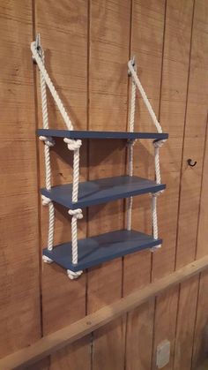 three shelves with ropes attached to them against a wooden wall