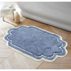 a bathroom rug with a blue design on the floor next to a white bath tub