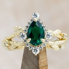 a close up of a ring with a green stone in the middle and white diamonds around it