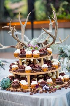 a wedding cake with deer antlers on the top and cupcakes in the middle