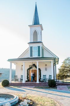 a man standing in the doorway of a white church with a steeple on top