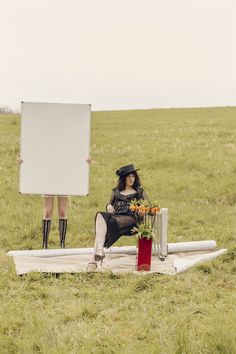 a woman sitting on top of a surfboard in a field next to a sign