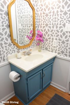 an image of a bathroom with wallpaper on the walls and a mirror above it