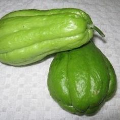 two green gourds sitting on top of a white tablecloth covered table cloth