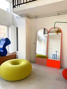 a living room filled with furniture next to a large mirror and colorful sculpture on the wall