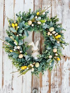 a wreath with yellow and green flowers hanging on a white wooden wall next to a door