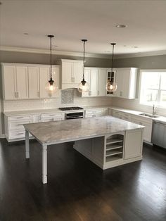 a large kitchen with white cabinets and marble counter tops, an island in the middle