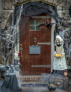 an outdoor halloween scene with creepy figures and decorations on the front door, including a ghost holding a plate of food