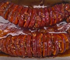 two sausages covered in sauce and nuts on top of a baking pan with other food items