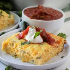 an omelet with sour cream on top and salsa in the bowl next to it