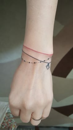 a woman's hand with a small tattoo on it and a red string attached to the wrist