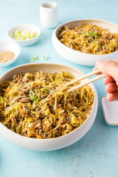 a person holding chopsticks over a bowl of food on a blue tablecloth