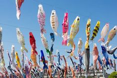 many different colored ribbons hanging from wires in the air with blue sky and clouds behind them