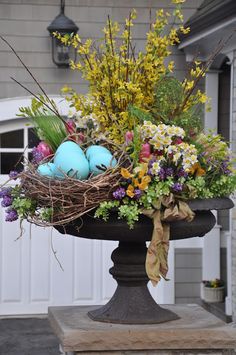 a bird's nest with blue eggs and flowers in front of a garage door