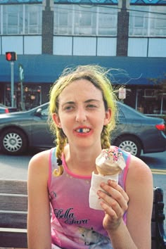 a woman sitting on a bench eating an ice cream cone with sprinkles