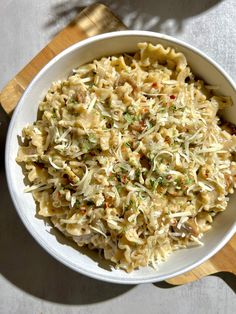 a white bowl filled with pasta on top of a wooden cutting board