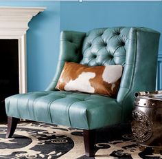 a blue chair sitting in front of a fireplace with a cow hide pillow on it