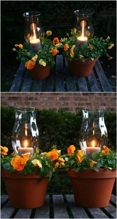 two vases filled with flowers and lit candles sitting on top of a wooden table