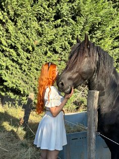 a woman with red hair standing next to a horse