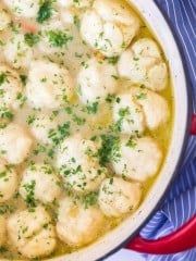 a red pot filled with dumplings covered in broth and parmesan cheese