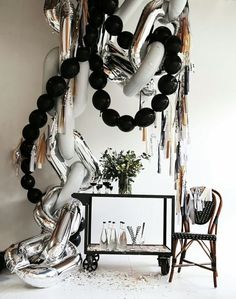 black and white balloons are hanging from the ceiling in front of a table with chairs