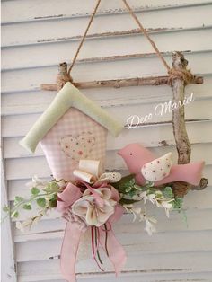 a birdhouse hanging on the side of a building with two birds and a pink bow