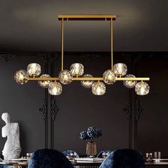 a modern chandelier hanging over a dining room table with blue chairs and vases