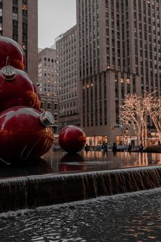 the large red balls are sitting on top of the fountain in the middle of the city