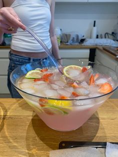 a woman standing in front of a bowl filled with ice and lemons next to a knife