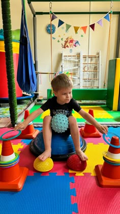 a little boy sitting on top of a potty chair in a play room filled with toys