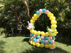 a balloon arch in the shape of a bunny with balloons attached to it, sitting on grass