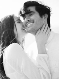 black and white photograph of a man kissing a woman's face on the cheek