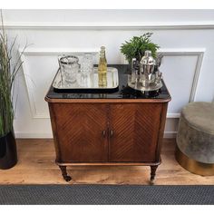 an old fashioned bar cart with drinks on it and two plants in the corner next to it