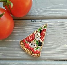 there is a piece of sequined pizza on the table next to some tomatoes