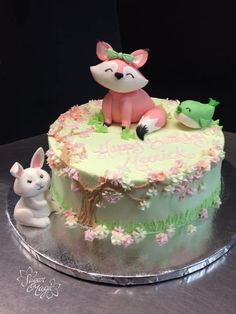 a birthday cake decorated with an animal and bunny figurine sitting on top of it