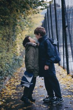 two people standing next to each other near a fence