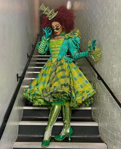 a woman dressed in green and yellow sitting on some stairs