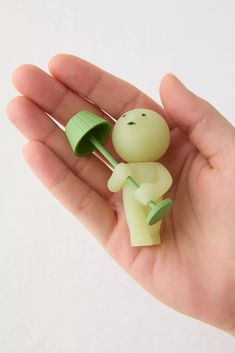 a hand holding a small toy with a green umbrella