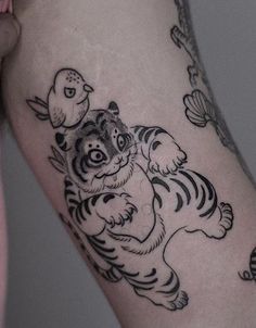 a woman's leg with a tiger and bird tattoo on the side of her thigh