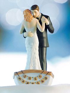 a bride and groom figurine standing on top of a snow covered hill with the words just married