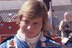 a young boy is posing for a photo in front of some fans at a race