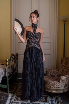 a woman in a black dress holding a fan