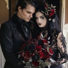 a man and woman dressed up in gothic garb with flowers on their head, holding each other