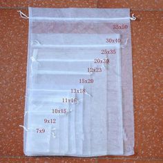 four pieces of clear plastic bags with numbers on them sitting on a tile floor in front of a brick wall