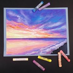 some crayons are laying on top of a painting