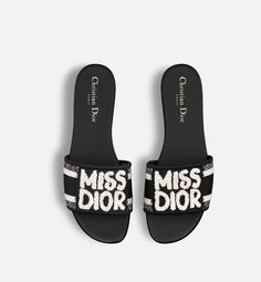 The Dway slide features a black upper embroidered with the white Miss Dior Graffiti signature, a nod to the 1967 debut ready-to-wear collection and a manifesto to Maria Grazia Chiuri's signature celebration of feminism. The sleek design slips on easily for a laid-back style. The shoe can be paired with other Miss Dior Graffiti creations.. 37.5 Graffiti Signature, Denim Swimsuit, Dior Star, Icon Shoes, Dior Book Tote, Maria Grazia Chiuri, Mens Travel Bag, Grown Women, Short Denim