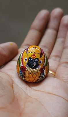 a hand holding a ring with a painted design on it