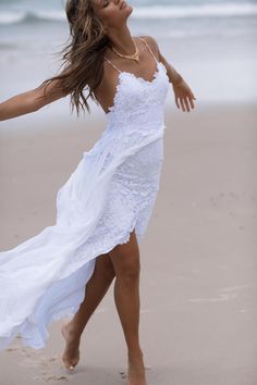 a woman in a white dress is dancing on the beach