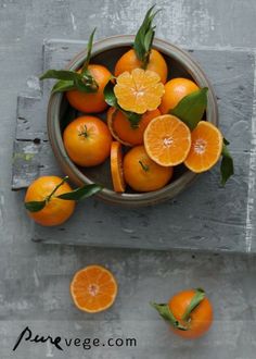 an overhead view of oranges in a bowl with leaves on the top and below